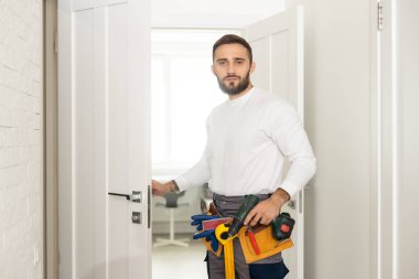 Portrait Young Male Carpenter Repairing Door Lock. clipart