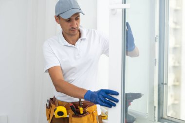 Usta plastik bir pencereye çift camlı yeni bir pencere takar.