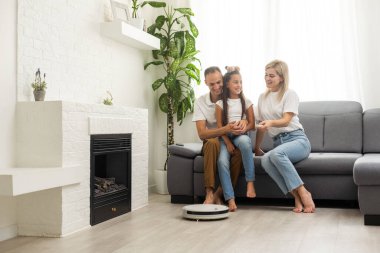Robotik elektrik süpürgesi evde çalışırken aile dinleniyor..