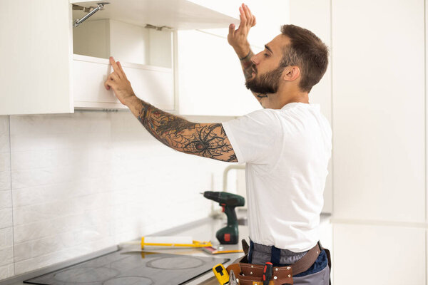 Male Worker Fixing Kitchen Hood With Screwdriver In Kitchen