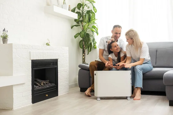 Family warming near electric heater at home