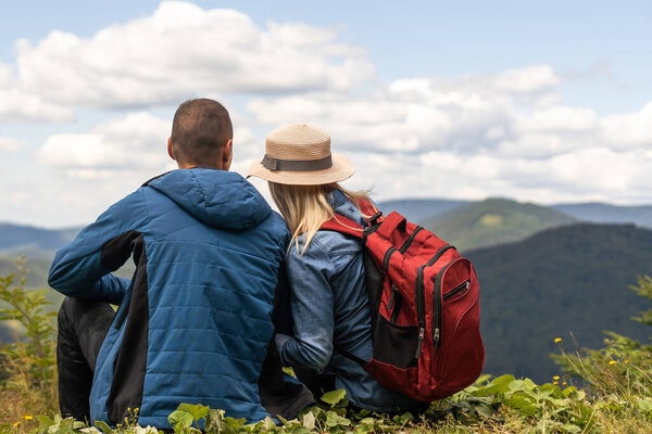 Hikers with backpacks relaxing on top of a mountain and enjoying the view.