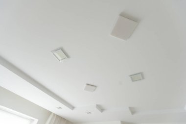 Halojen lambalı asma tavan ve boş bir oda ya da evde alçıpan inşaatı. Gergin tavan beyaz ve karmaşık şekil. Yüksek kalite fotoğraf