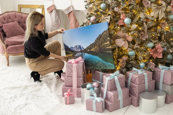 Canvas print with gallery wrap. Woman hangs photography on white wall. Hands holding photo canvas print.