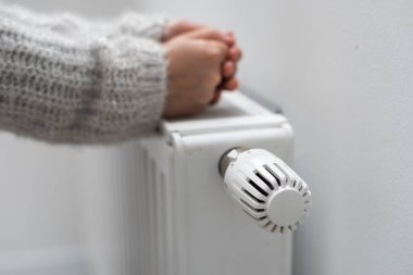 Çocuklar ellerini ısıtıcının yanında ısıtıyorlar. Isıtma mevsiminde benzin tasarrufu