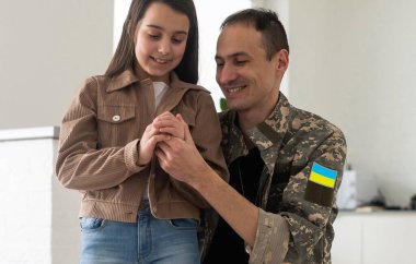 Ukrayna askeri üniformalı asker kızına sarılıyor. Aile toplantısı.