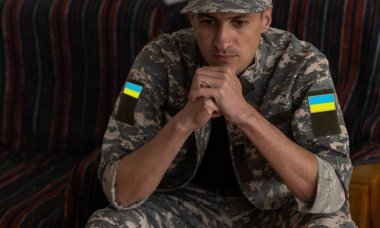 Üzgün bir asker evde oturup düşünüyor.