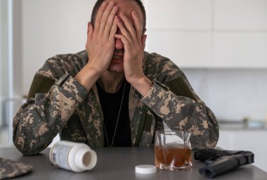 Genç adam kamuflaj yağmurluğu giyer ve farklı jestler gösterir. Stüdyodaki gri arka planda. Yüksek kalite fotoğraf