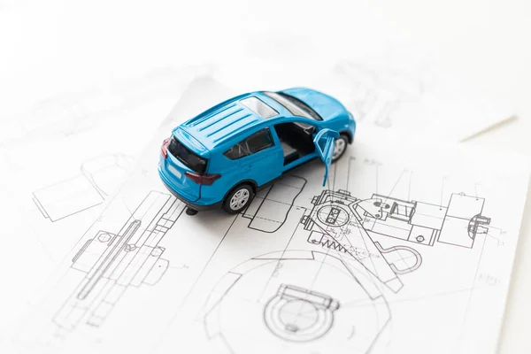 small car model and blueprint sheets. High quality photo