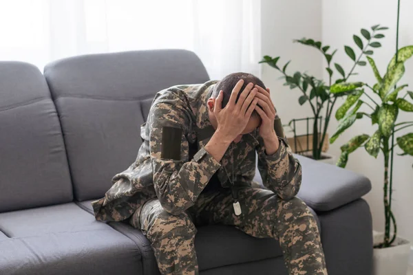 Having flashbacks. Post traumatic stress disorder. Soldier in uniform sitting indoors. High quality photo