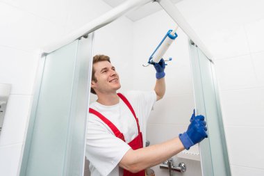 İşçiler duş kabininin cam kapağına silikon conta takıyorlar.