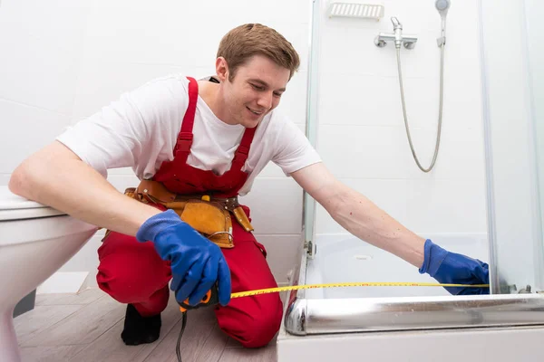 Ung Man Uniform Reparerar Duschdörren Badrummet Reparatör Reparerar Duschkabinen — Stockfoto