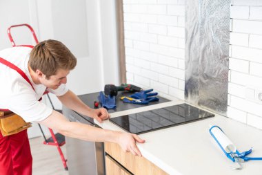 craftsman installs hob in kitchen. Household Appliance Installation Services Concept.