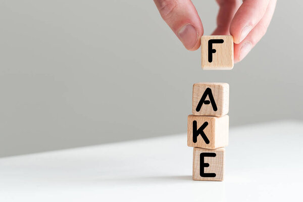 Рука сальто древесины куба изменить слово Факт или подделка. Концепция Дня дураков. Высокое качество фото