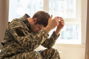 Orta yaşlı üzgün, çaresiz askerin portresi terapi seansı sırasında kameraya düşünceli bakıyor. Depresyondan muzdarip engelli asker. Travma sonrası stres bozukluğu. Yatay çekim.