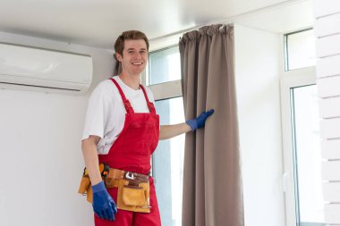 Perde takan bir erkek işçi.