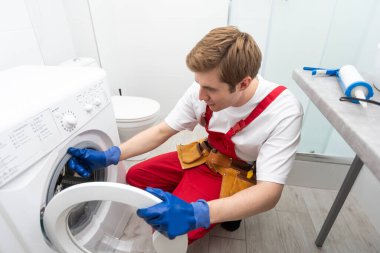 tesisatçı ev yapımı çamaşır makinesini tamir ediyor.