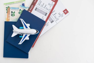 Beyaz arka planda biletleri olan oyuncak uçak ve pasaport..