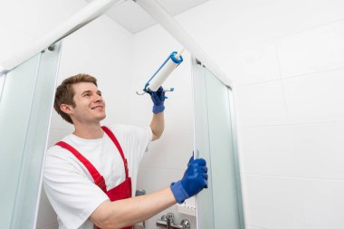 İşçiler duş kabininin cam kapağına silikon conta takıyorlar.