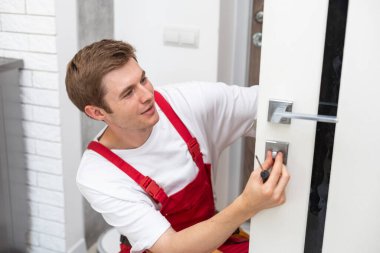 Genç adam evin kapısını tamir ediyor..