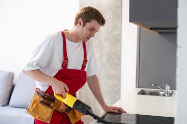 Genç yakışıklı adam evi temizliyor. Çekici adam mutfakta elektrikli süpürge tutuyor..