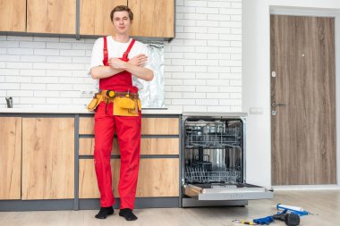 Bulaşık makinelerinin tamiri. Tamirci mutfakta bulaşık makinesini tamir ediyor..