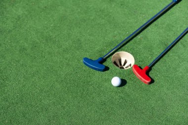 Sentetik çimlerin üzerinde golf topları olan renkli golf sopaları..