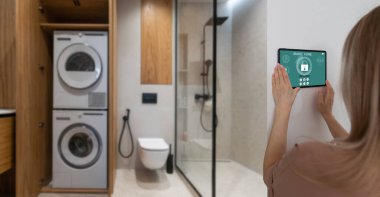 Akıllı ev sistemini kullanan ya da evden çıkmadan önce modern alarm sistemini çalıştıran hoş bir kadın. Mutlu kadın eve ya da daireye döndüğünde kolay güvenlik teknolojisini kapatıyor..