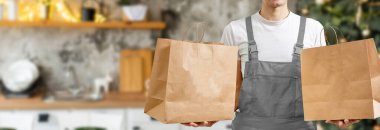 Paket çantalı yakışıklı teslimatçı büyük bir gülümsemeyle mutlu.