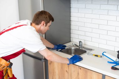 Tesisatçı mutfaktaki musluktan su akışını kontrol ediyor, yakın plan. Onarım servisi.