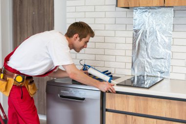 craftsman installs hob in kitchen. Household Appliance Installation Services Concept.