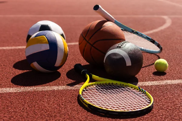 Set of sport equipment, soccer basketball balls and tennis rackets.