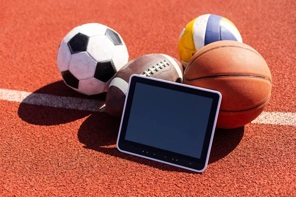 balls and tablet computer on color background. Concept of sports bet.
