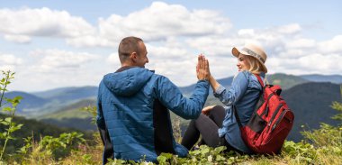 Hikers with backpacks relaxing on top of a mountain and enjoying the view.