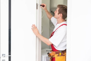 İç kapıların delinmesi ve kurulumu, zanaatkar kapı çerçevesinde el matkabı, kapı ve kurulum ile bir delik açar.