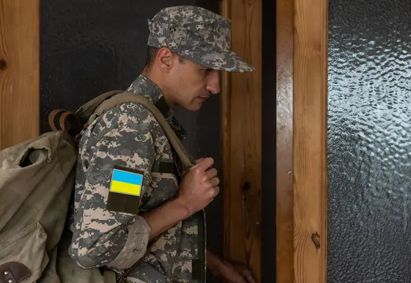 Ukrainian soldier wearing military uniform with flag and chevron depicting trident - Ukrainian national symbol flag.