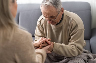 Genç fizyoterapistle rehabilitasyon işlemine katılan yaşlı bir erkek emeklinin başından vurulmuş. Yürüme engelli emekli bir adam profesyonel yardıma minnettar.