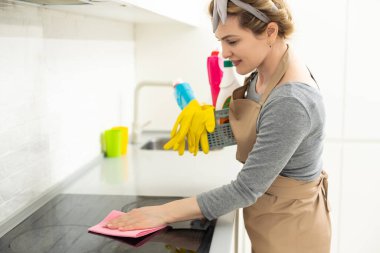Hafta sonu ödevi. Genç ve güzel bir kadın evdeki rahat oturma odasını temizliyor. Parlak bir odada, ev kıyafetleri ve lastik eldivenler içinde güzel bir kadın.