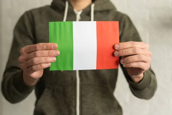 Person holding a Italian flag on a white background.