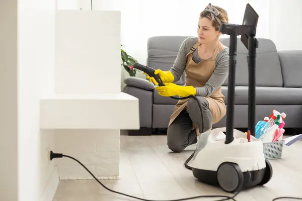 Woman using steam vapor cleaner in living room.