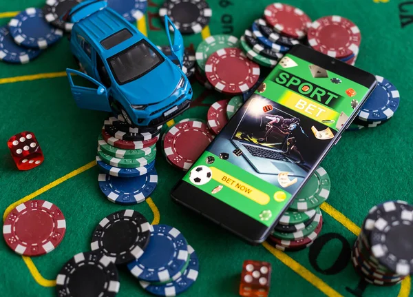 pile of casino chips and toy car, smartphone with betting on sports.