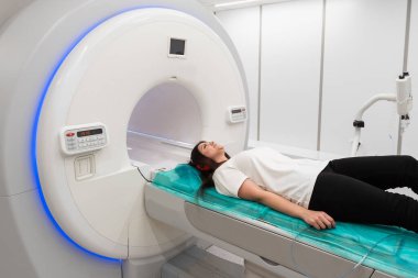 Modern hastane laboratuvarında bir hastaya tıbbi tomografi ya da MRI taraması yapın. Radyografi bölümünün içi. Beyaz odada teknolojik olarak gelişmiş ekipmanlar var. Manyetik rezonans tanılama makinesi.