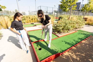 Anne ve küçük kızı sahada topa vurmak için alıştırma yapıyorlar. Yüksek kalite fotoğraf