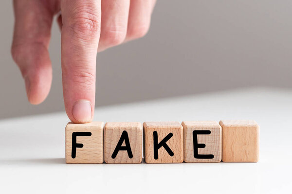 Крупный план бизнесвумен держит кубики со словом FAKE. Высокое качество фото