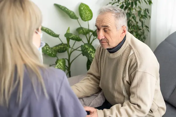 Portrait of mature female psychiatrist interviewing handicapped senior man during therapy session, copy space