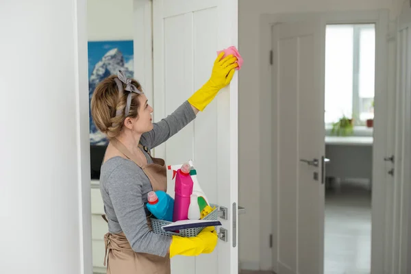Young woman doing house chores. Woman holding cleaning tools. Woman wearing rubber protective yellow gloves, holding rag and spray bottle detergent. Its never too late to spring clean.