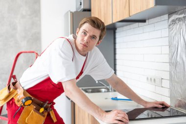 craftsman installs hob in kitchen. Household Appliance Installation Services Concept