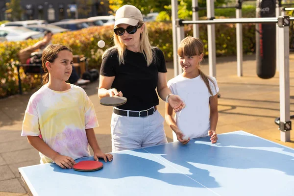 Family playing table tennis in the summer outdoors. High quality photo