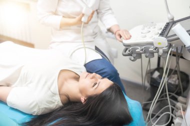 Klinikte ultrason cihazı kullanan uzman bir doktor..