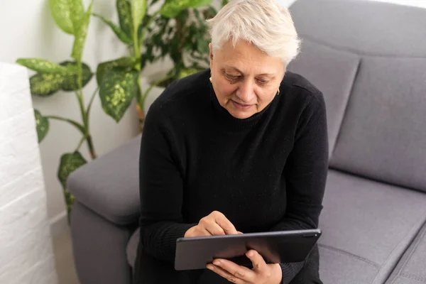 Senior elderly woman using tablet.